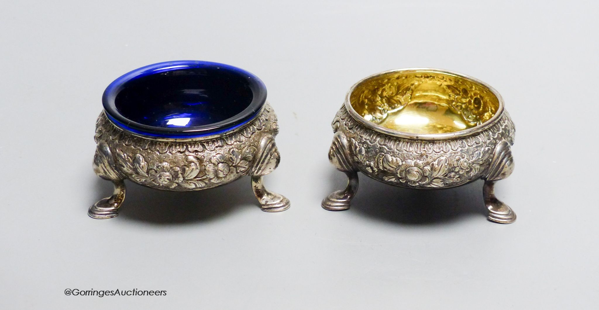 A pair of Georgian embossed silver cauldron salts, marks indistinct, 5oz. gross, 7.5 cm wide, One later blue glass liner